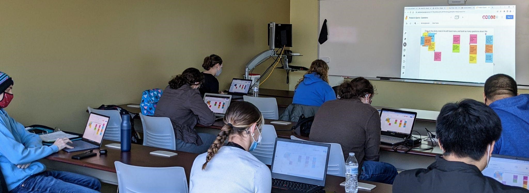Students using post-it note program on laptops during class.