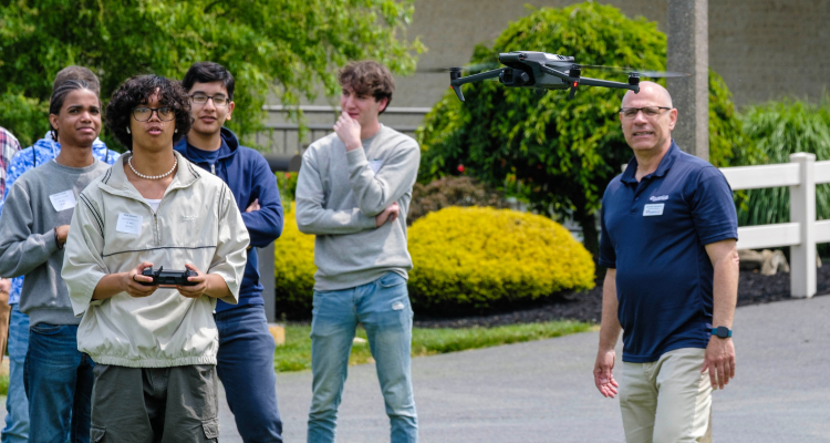 Students watch as one of their classmates tries flying a drone as Atlantic Cape Associate Professor Anthony Esposito looks on during Aviation Day